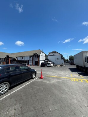 A parking lot with a black car, a red traffic cone, and a white truck. - Grosvenor Motor Inn (Hamilton)