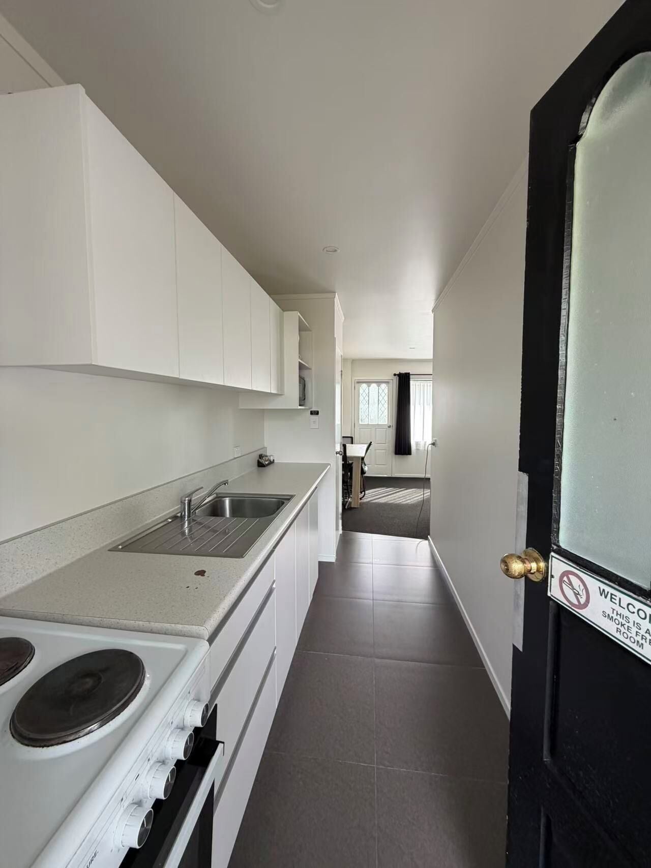 A modern kitchen with white cabinets, a stainless steel sink, and a stove.