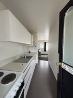 Una cocina moderna con armarios blancos, un lavamanos de acero inoxidable y una estufa.