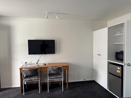 Una pequeña kitchenette equipada con microondas, refrigerador y televisor de pantalla plana montado en la pared.