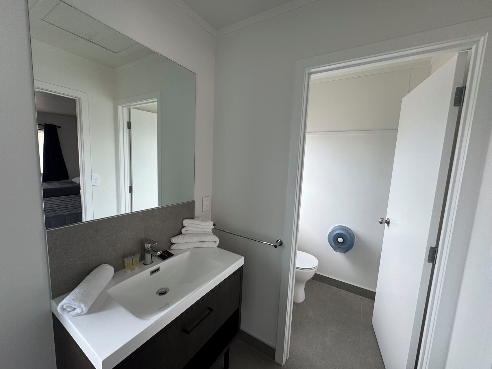 Une salle de bain moderne avec un lavabo blanc, un miroir et des toilettes.