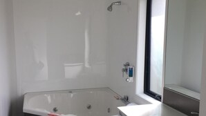 Un baño moderno con una bañera grande, un lavamanos separado y un espejo.
