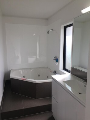 A modern bathroom with a large bathtub, a separate sink, and a mirror. - Grosvenor Motor Inn (Hamilton)