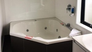 Un baño moderno con una bañera grande independiente, un cabezal de ducha y una ventana.