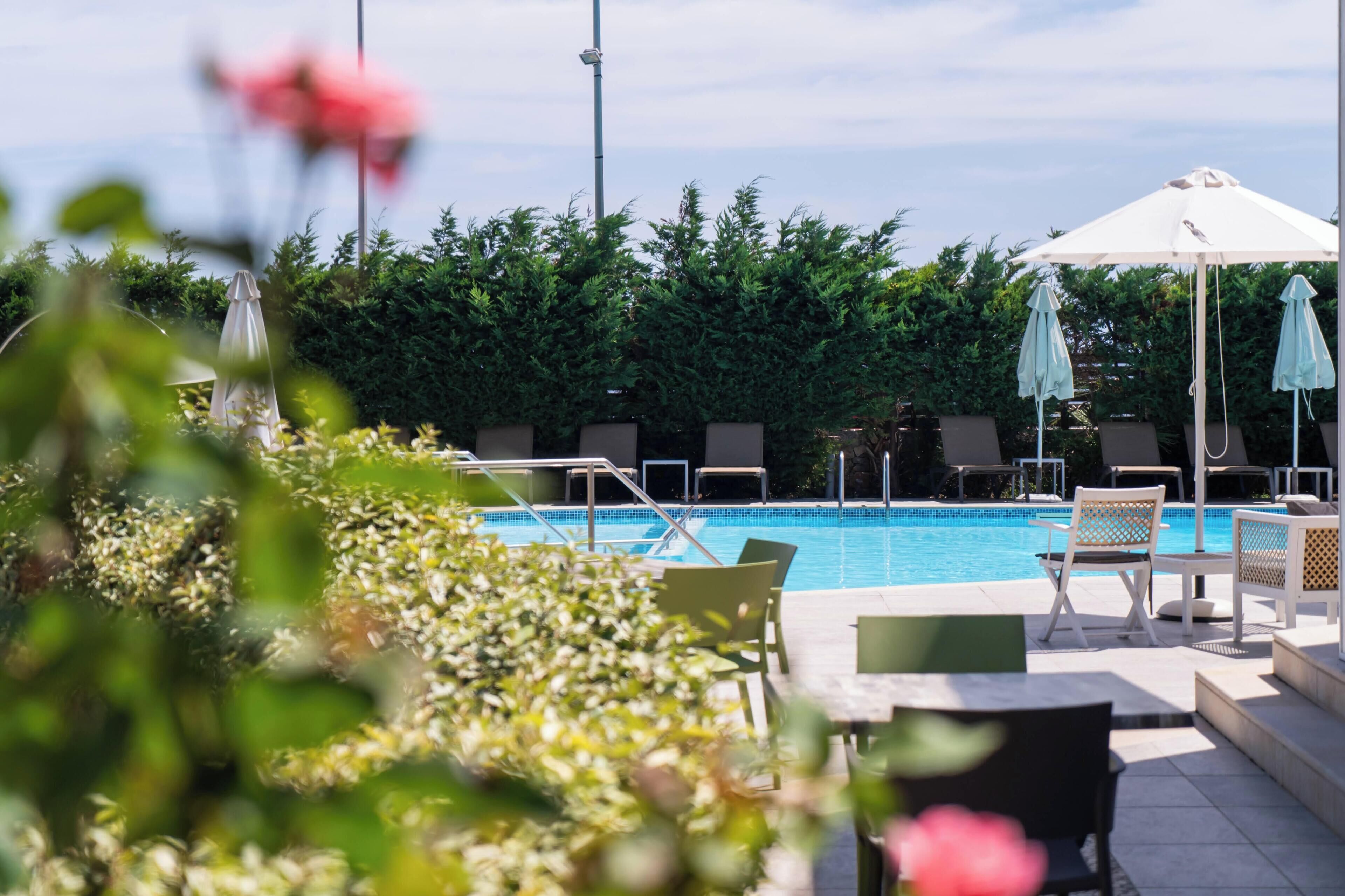 A pool area with lounge chairs, umbrellas, and a view of the pool.