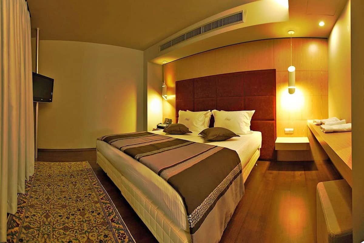 A hotel room with a large bed, a bedside table, a TV, and a bathroom.