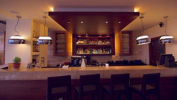 Zona de bar con mostrador, asientos y estantes llenos de botellas.