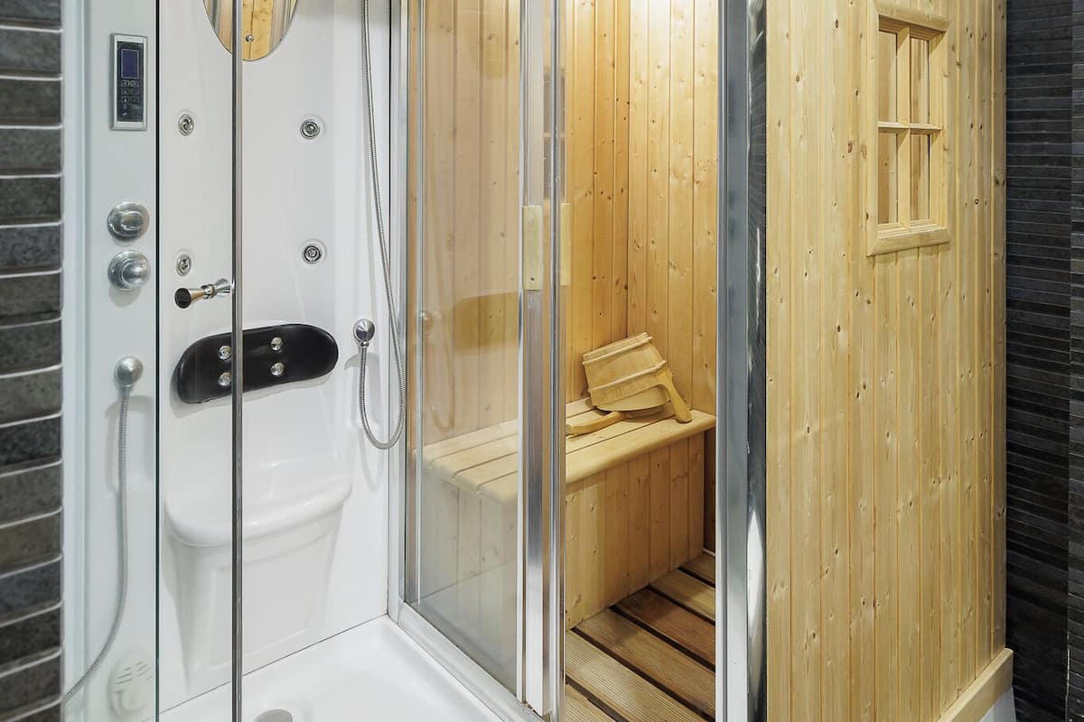A sauna with a glass enclosure, wooden benches, and a control panel.