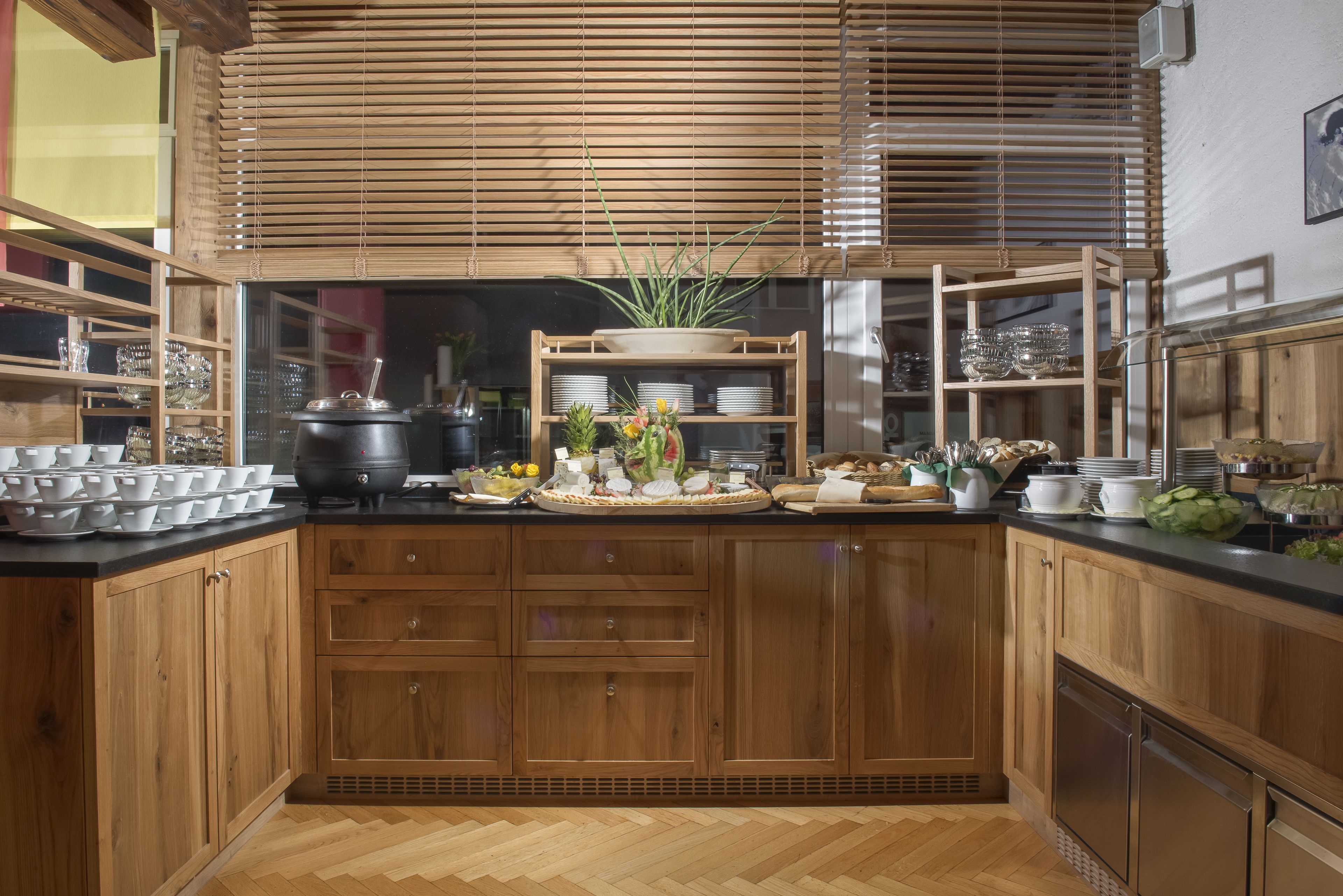 A kitchen with wooden cabinets, a black countertop, and a variety of dishes and utensils.