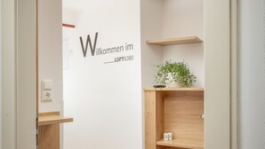 Et moderne interiør med en trappe i træ, et velkomstskilt og en lille plante på en hylde.