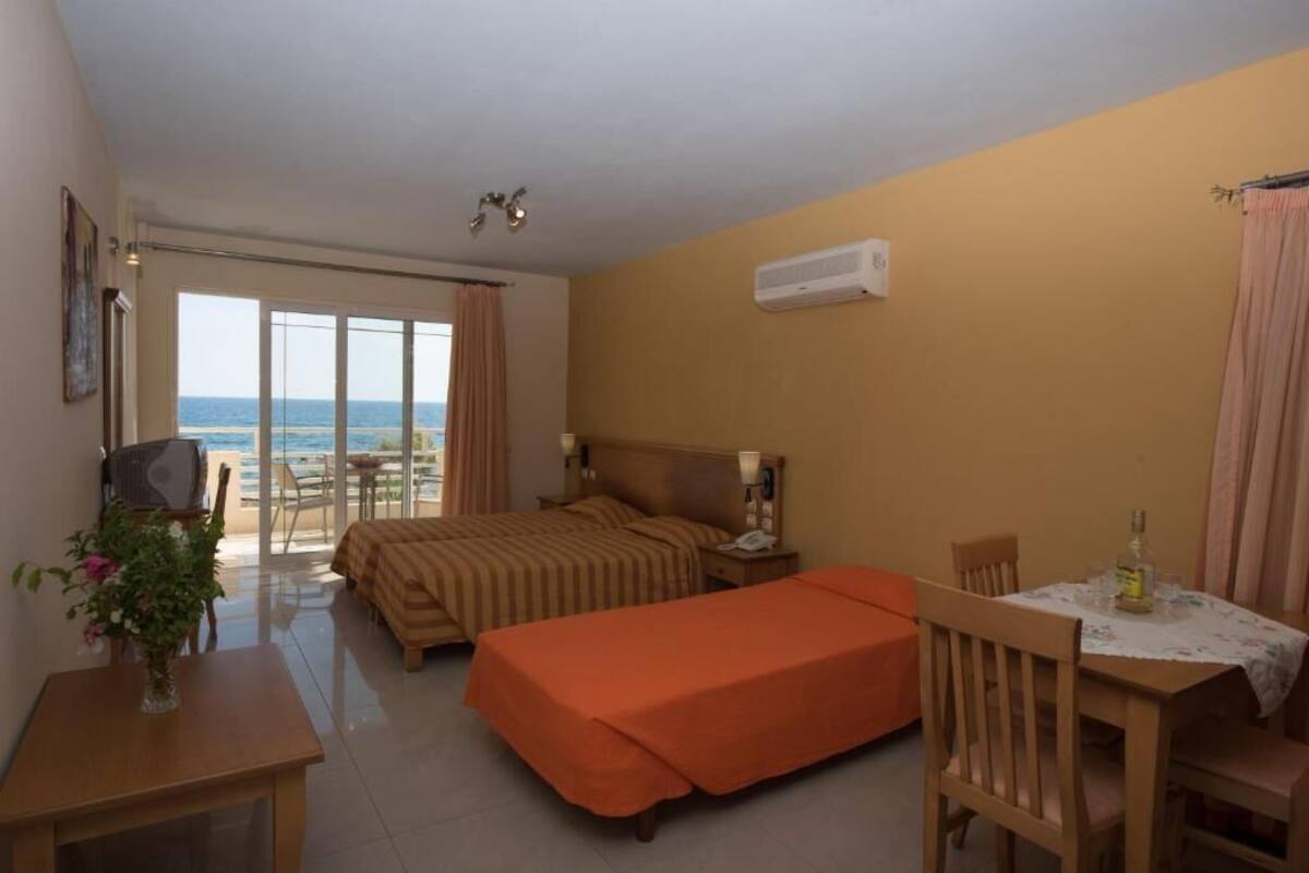 Habitación de hotel con cama, escritorio, silla, mesa y vista al mar.