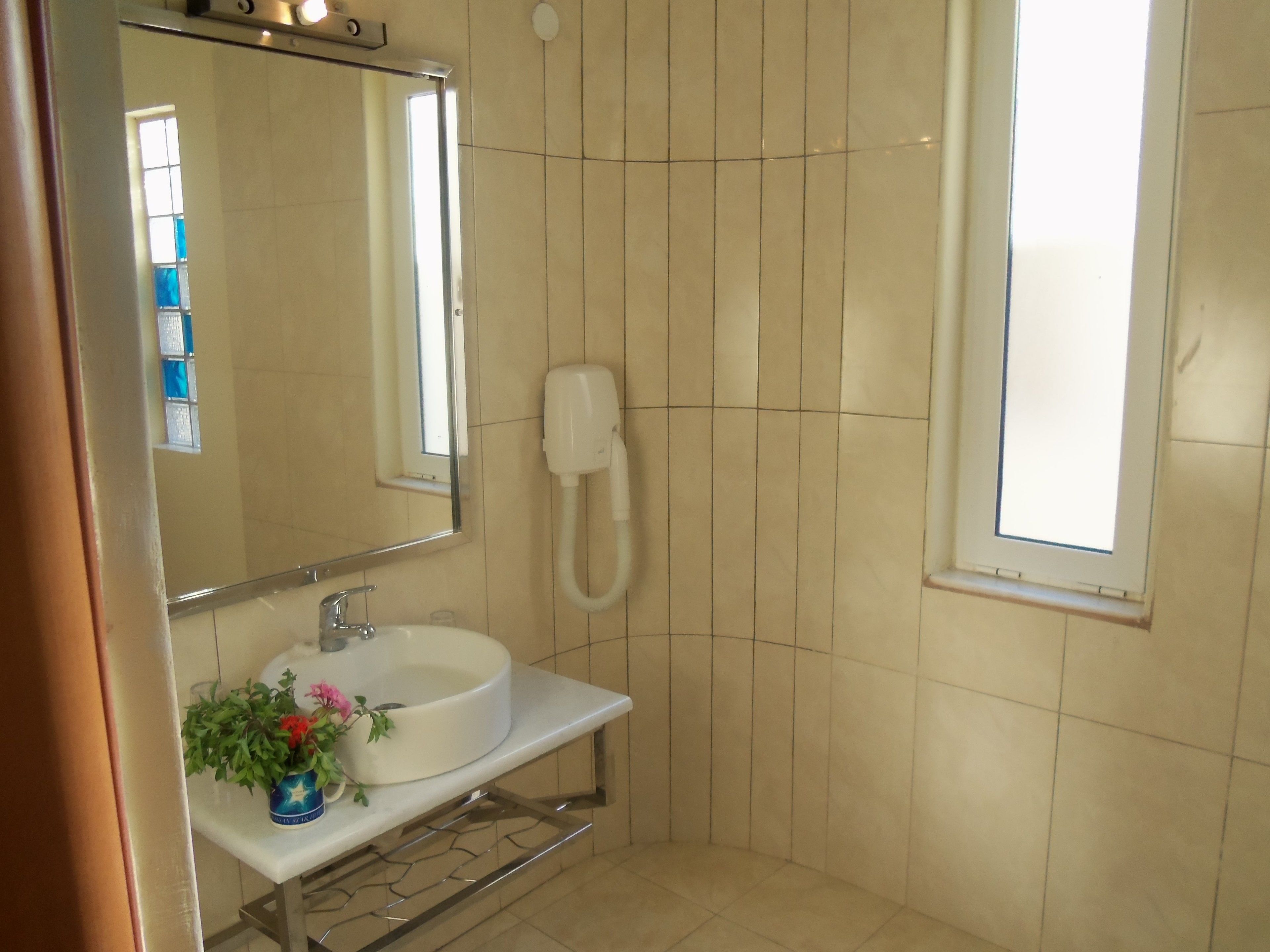 A bathroom with a sink, mirror, and a handheld shower.
