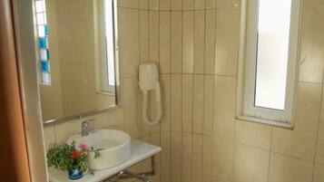 A bathroom with a sink, mirror, and a handheld shower.