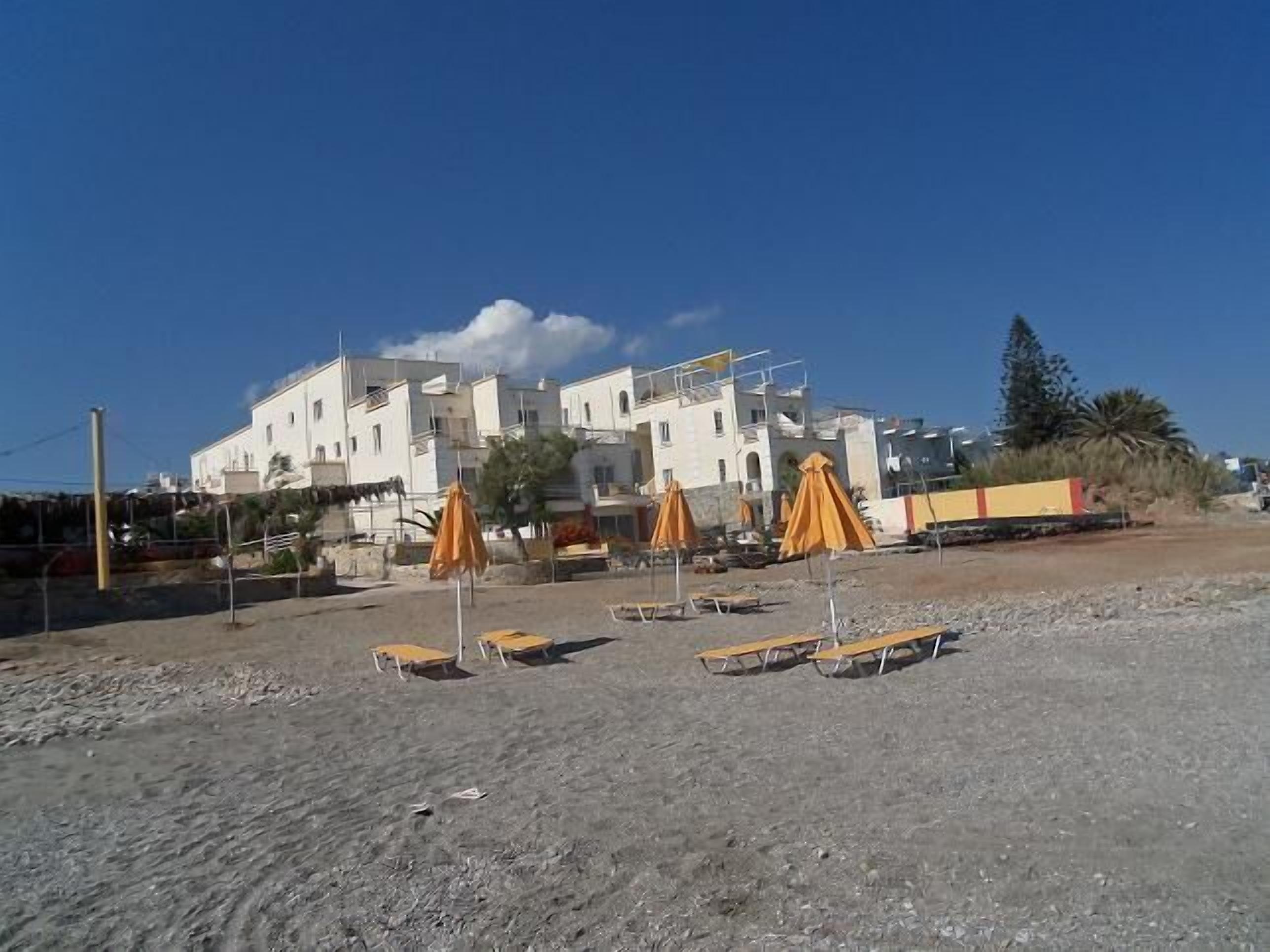 Una propiedad frente a la playa con varias habitaciones, zona de estar exterior y vista despejada al mar.