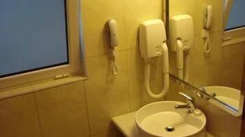 A bathroom with a sink, a mirror, and two phones mounted on the wall.