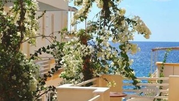Un balcon avec des chaises blanches et une vue sur la mer.