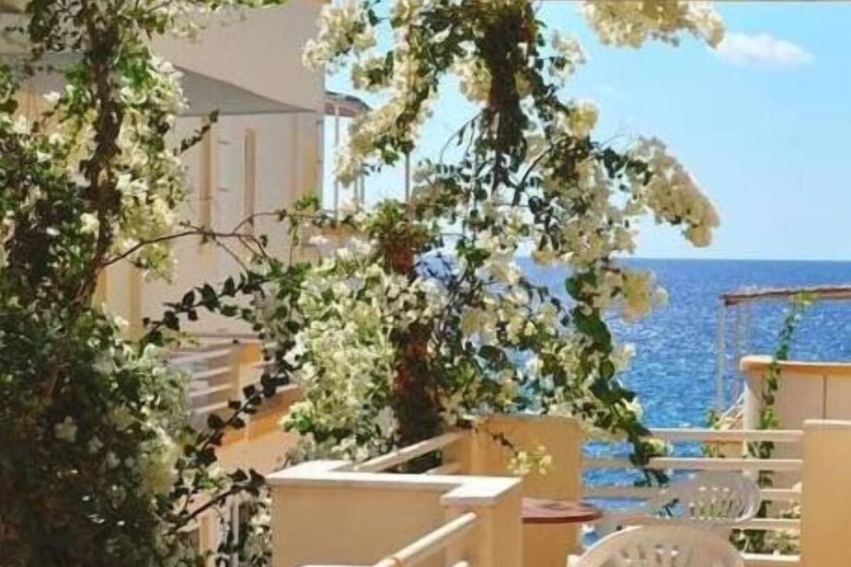 Un balcón con sillas blancas y vista al mar.