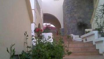A narrow staircase leading to a building entrance, surrounded by greenery and a stone wall.