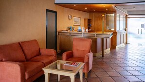 A hotel lobby with a sofa, armchair, and a small table with a magazine. - Klusenhof (Lippstadt)