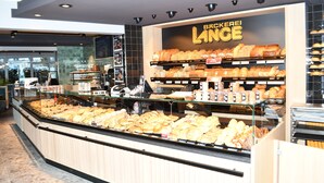 A bakery display with various baked goods, a cash register, and a sign reading 'Bakerie Lince'. - Klusenhof (Lippstadt)