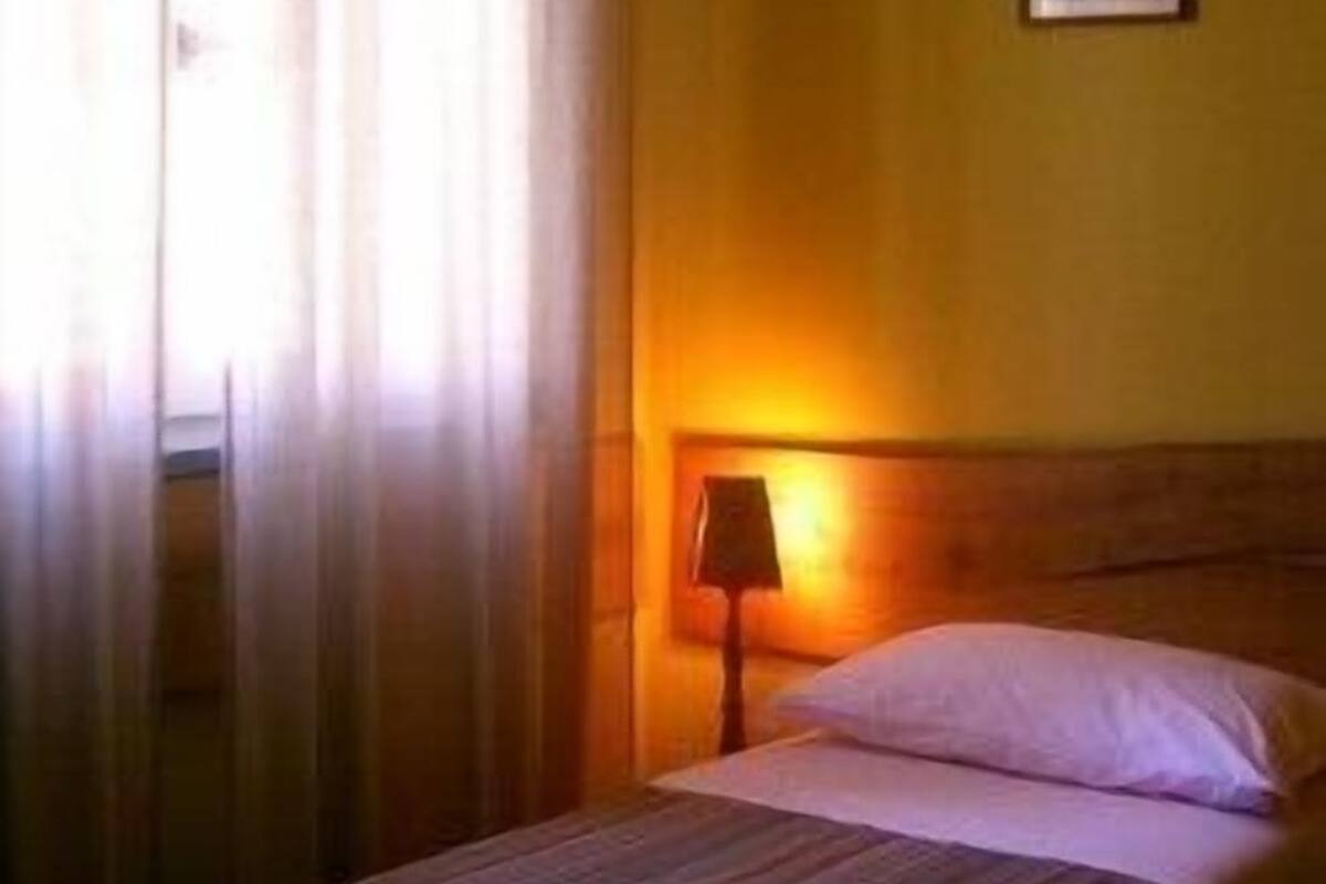 Ein Hotelzimmer mit Bett, Nachttisch, Lampe und Wandleuchte.