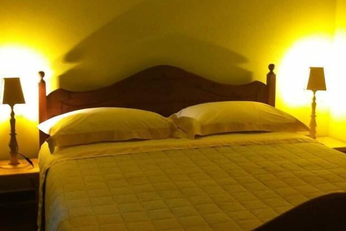 Ein Bett mit Holz-Kopfteil, zwei Nachttischlampen und einer Wandleuchte.