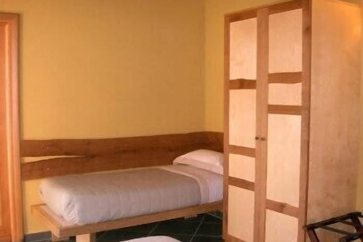 Ein Einzelbett mit Holz Kopfteil und ein Kleiderschrank mit Spiegel.