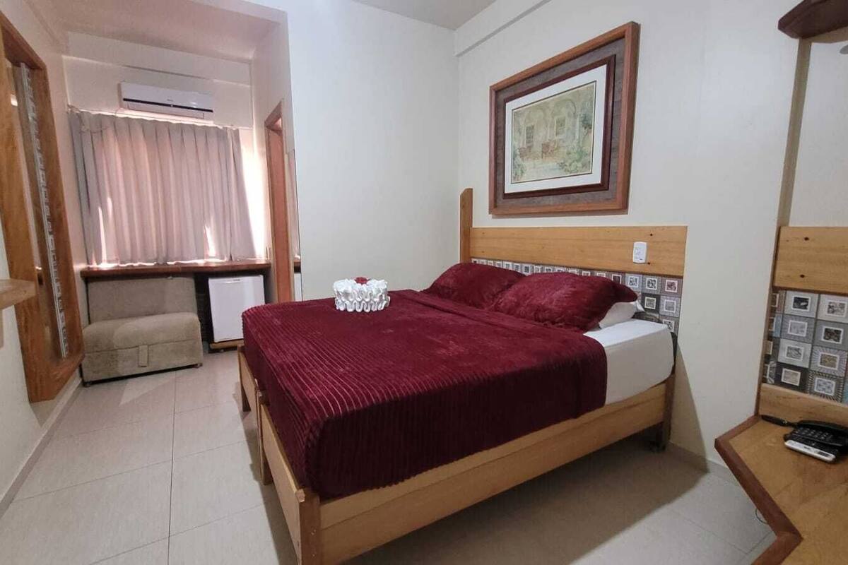 A bedroom with a wooden bed, a bedside table with a phone, and a framed picture on the wall.