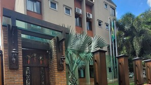 Un edificio de varios pisos con una entrada de ladrillo, puerta de vidrio y portón metálico.