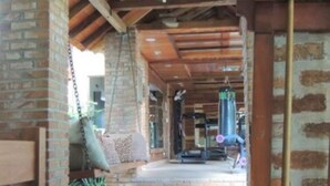 Un espacio al aire libre techado con piso de madera, paredes de ladrillo y estructura de techo de madera.
