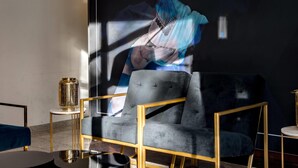 A modern room with a dark blue sofa, a gold-framed armchair, and a small side table with a decorative vase. - Aspire Elements Reutlingen, Trademark Collection by Wyndham (Reutlingen)