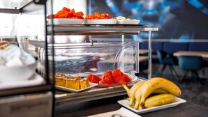 A breakfast buffet with various food items including sliced fruits, pastries, and a banana on a tray. - Aspire Elements Reutlingen, Trademark Collection by Wyndham (Reutlingen)
