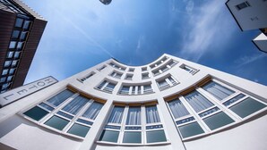 A modern building with a curved facade, multiple windows, and a clear sky. - Aspire Elements Reutlingen, Trademark Collection by Wyndham (Reutlingen)
