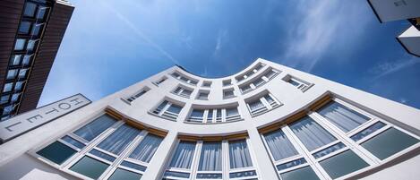 A modern building with a curved facade, multiple windows, and a clear sky.