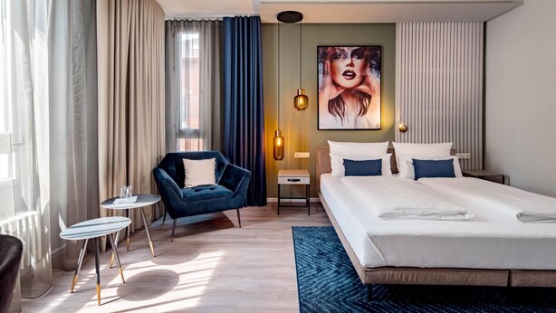 A hotel room with a bed, a desk, a chair, and a painting on the wall. - Aspire Elements Reutlingen, Trademark Collection by Wyndham (Reutlingen)