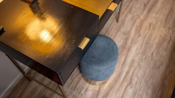 A wooden table with a golden top and a blue round ottoman beside it.