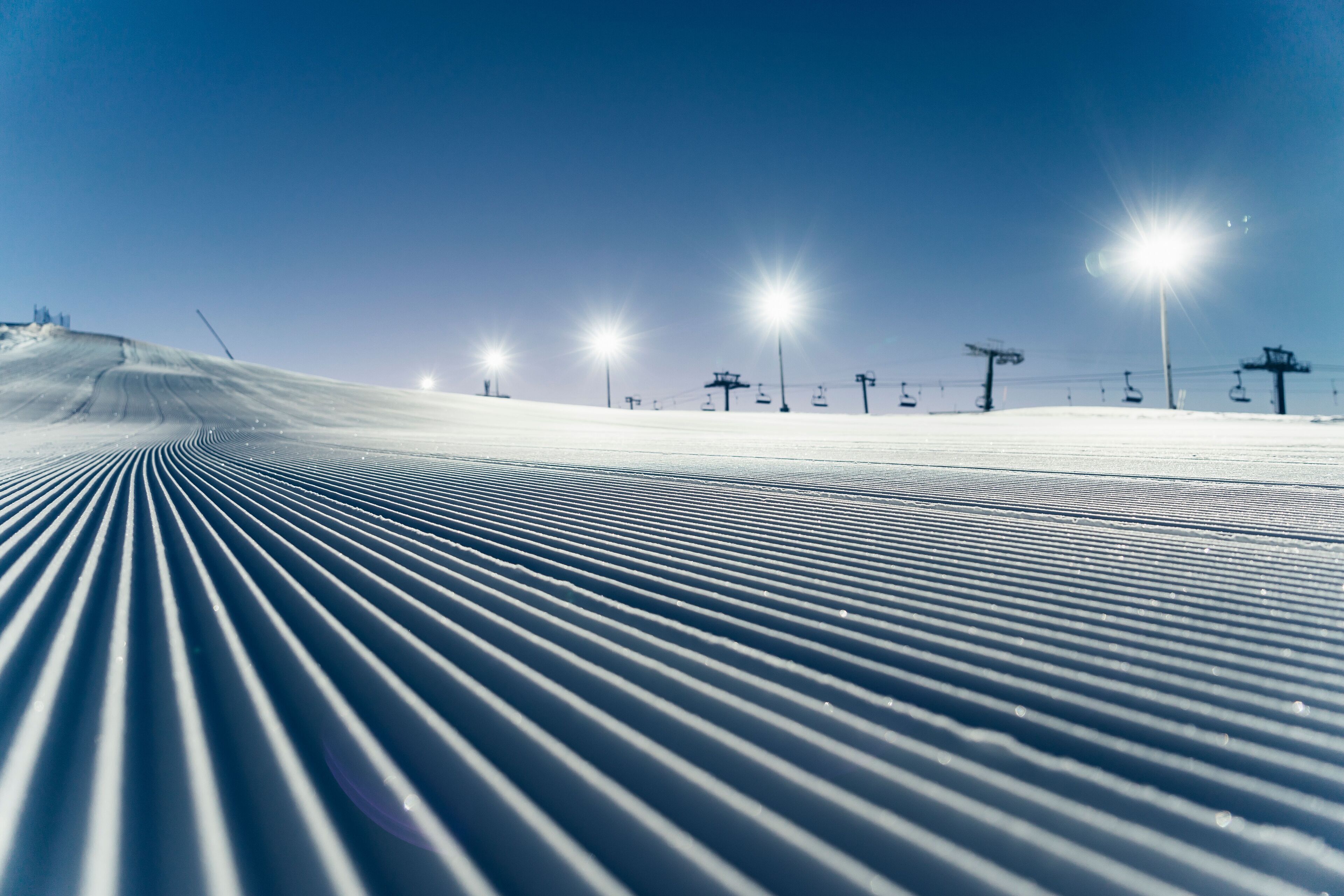 Une piste de ski avec un tracé bien défini et des remontées mécaniques en arrière-plan.