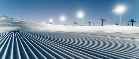 Une piste de ski avec un tracé bien défini et des remontées mécaniques en arrière-plan.
