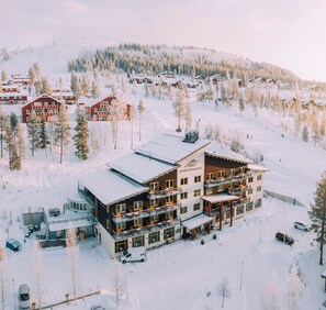 Un hôtel à plusieurs étages avec une piste de ski en arrière-plan.