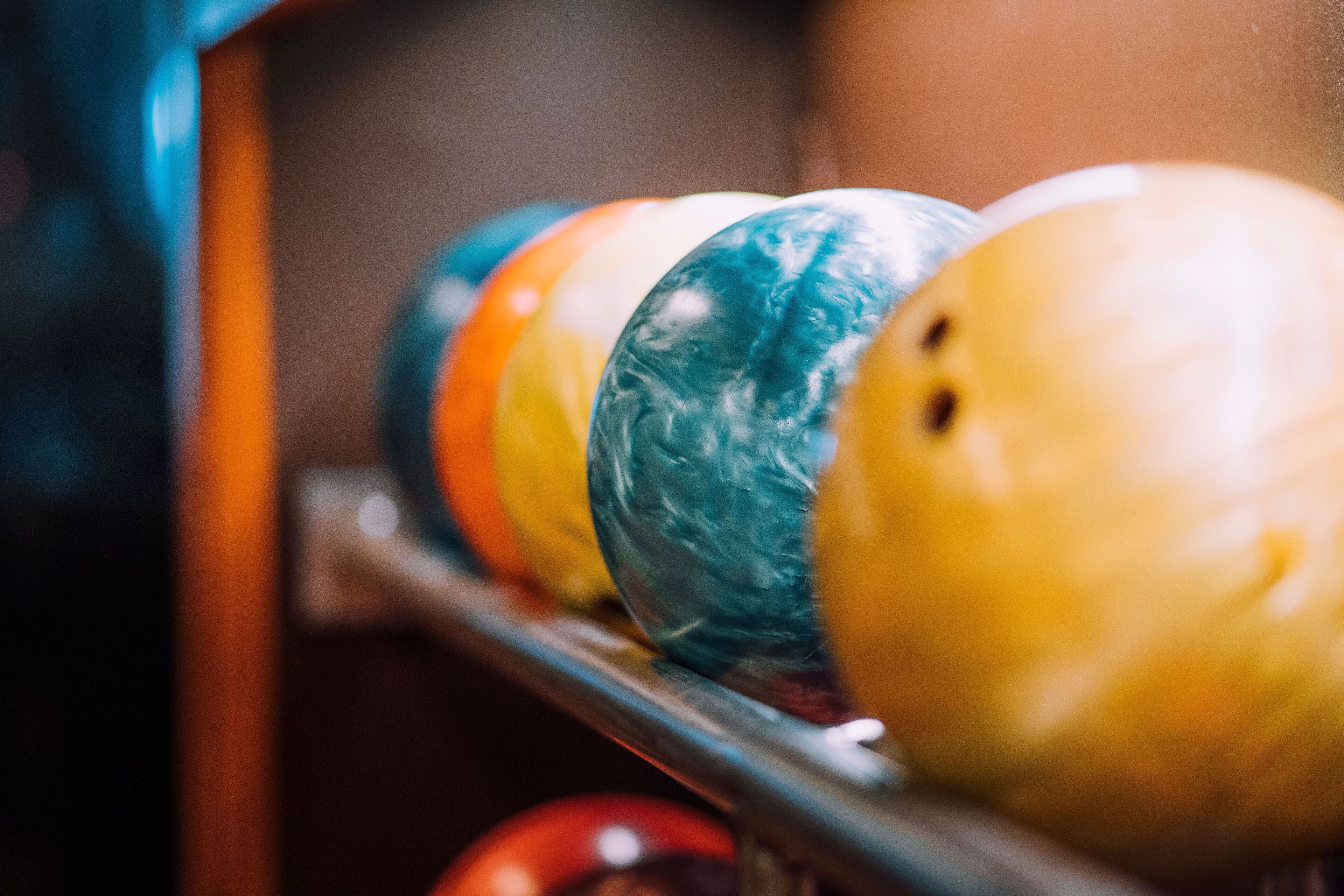 A row of bowling balls on a rack.