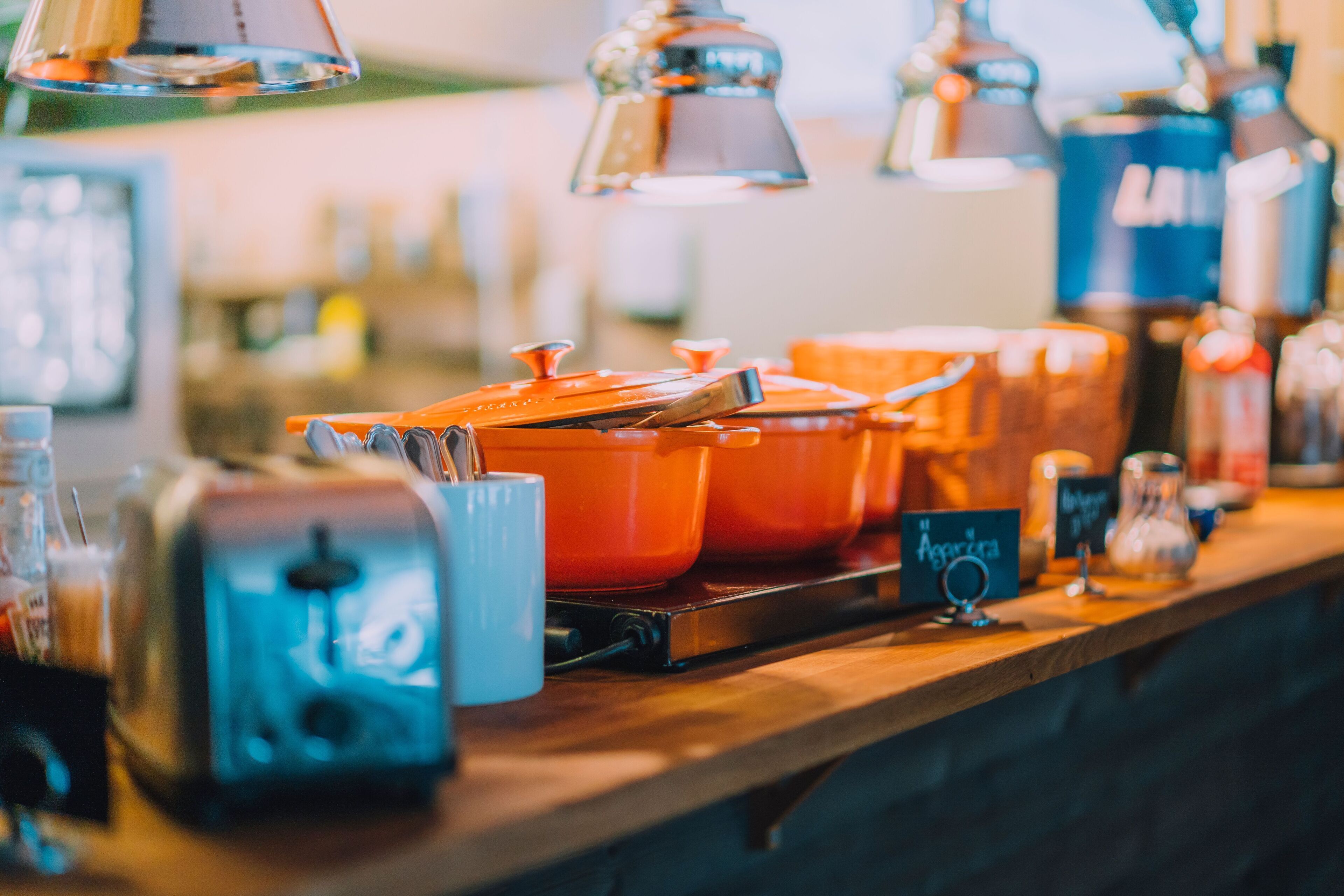 Una encimera de cocina con diferentes electrodomésticos y recipientes, incluyendo un tostador y ollas naranjas.