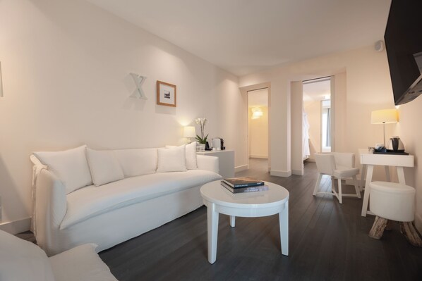 A modern living room with a white sofa, a round coffee table, and a small white side table.