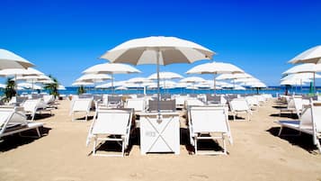 Aan een privéstrand, ligstoelen, parasols, strandlakens