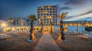 Un hotel con un patio central, palmeras y un área de descanso frente a la playa.