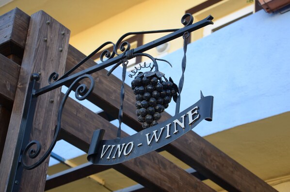 A metal sign with "VINO-WINE" and a bunch of grapes. - Tikar (Garrucha)