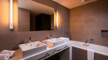 A modern bathroom with two sinks, a bathtub, and a large mirror.