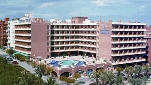 Ein mehrstöckiges Hotel mit Schwimmbad im Erdgeschoss, ausgestattet mit Balkonen auf jeder Etage.