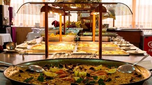 Ein Buffet mit Meeresfrüchte-Paella im Vordergrund und verschiedenen weiteren Speisen im Hintergrund.