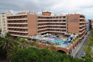 Ein mehrstöckiges Hotel mit Poolbereich auf dem Dach, inklusive Wasserrutsche und Sonnenschirmen.