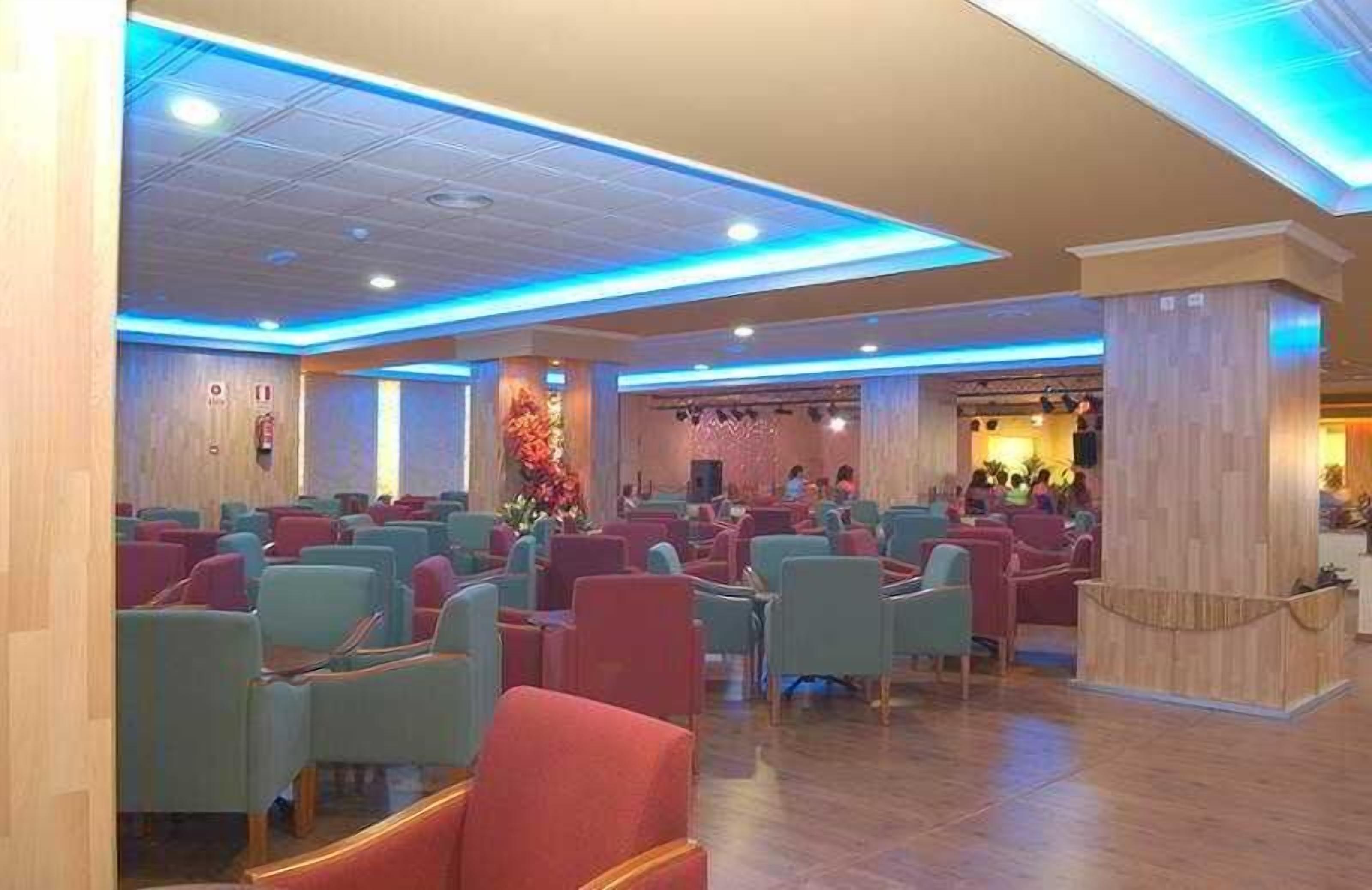 A hotel lobby with rows of seating, a reception area, and a decorative wall.
